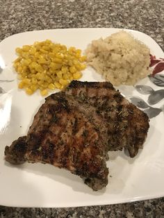 a white plate topped with meat, rice and corn