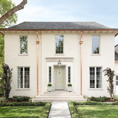 a white brick house with two story windows and an entry way leading to the front door