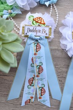 two ribbons with sea turtles on them are next to some flowers and ribbon clips that say daddy to be