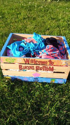 a wooden box filled with clothes on top of a lush green field