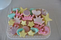 decorated cookies in the shape of princess crowns and stars on a clear plastic platter