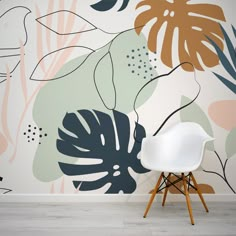 a white chair sitting in front of a wall with plants painted on it and a plant mural behind it