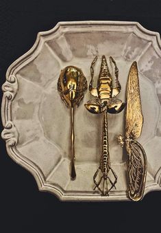 there are three spoons and two forks on the plate with dragonfly designs in them