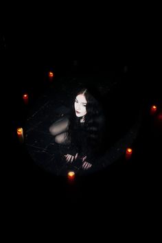 a woman laying on the ground surrounded by candles