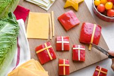 someone is cutting up some food on a wooden board with cheese and other foods in the background