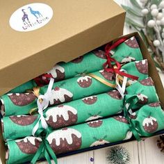 four wrapped christmas presents in a box on a table next to pine cones and decorations