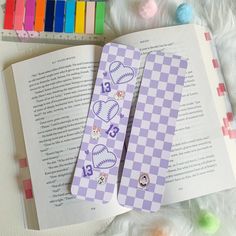 two bookmarks with baseball and heart on them sitting next to an open book, surrounded by colored crayons