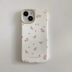 an iphone case with pink flowers on it sitting on a white surface next to a pair of glasses