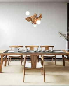 a dining room table with chairs and lights hanging from it's ceiling, in front of a white wall