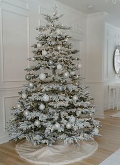 a white christmas tree with silver ornaments on it