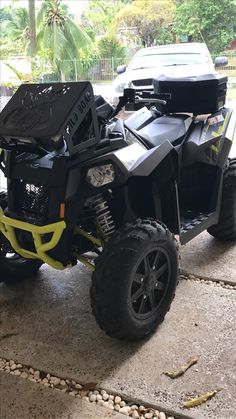 a black and yellow four - wheeler parked in front of a car