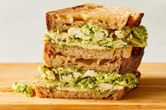 two halves of a sandwich stacked on top of each other with avocado toppings