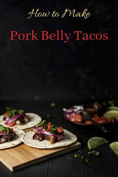 three pork belly tacos on a cutting board with limes and cilantro