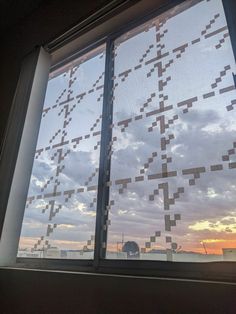 a window with some squares on it and the sun setting in the sky behind it