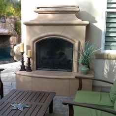 an outdoor living area with fireplace, chairs and coffee table in front of the fire place