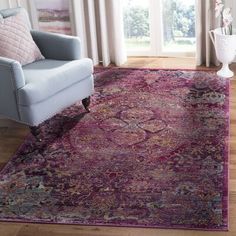 a living room with a blue chair and purple rug on the hardwood floor next to a window