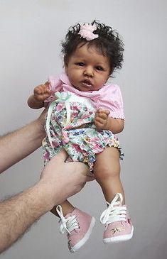 a man holding a baby in the air with one hand on it's shoulder