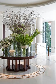 a table with vases and flowers on top of it in front of a window