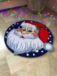 a santa clause rug on the floor with christmas lights around it and a potted plant in the corner