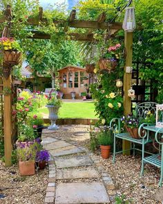 a garden with lots of plants and flowers on the ground, along with a stone path that leads to an outdoor seating area