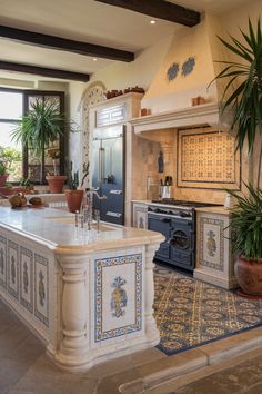 This spacious kitchen combines traditional Spanish elements with a luxurious touch.

Intricately painted tile accents frame the stove and island, adding vibrant color and artistry.

The dark beams and potted greenery complete the sophisticated yet inviting look.