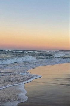 two people walking on the beach at sunset