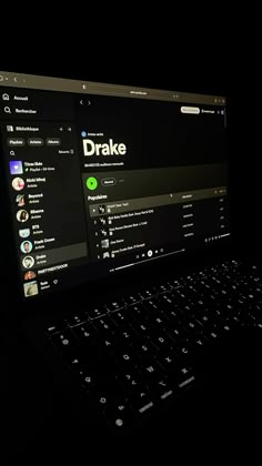 an open laptop computer sitting on top of a black table in the dark with its screen lit up