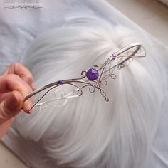 Adorn yourself with regal beauty and grace wearing our exquisite Purple Dream tiara. This enchanting headpiece is meticulously handcrafted with non-tarnish silver plated wire, delicately woven to create an intricate design that exudes elegance and charm. Adorned with sparkling crystals, this tiara captures the essence of a fairy tale dream. The Purple Dream tiara features a captivating arrangement of shimmering crystals that reflects a mesmerizing spectrum of purple hues, adding a touch of enchantment to your look. The non-tarnish silver plated wire enhances the tiara's durability and ensures it maintains its lustrous shine for years to come. Perfect for weddings, proms, quinceañeras, or pageants, this tiara is a statement piece that will make you feel like royalty on your special day. The Amethyst Tiara Crowns, Princess Circlet, Purple Tiara, Fantasy Jewelry Magic, Elven Circlet, Elven Tiara, Crown Aesthetic, Purple Crown, Purple Accessories