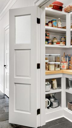 an open pantry door in a kitchen with white cabinets and shelves filled with food items