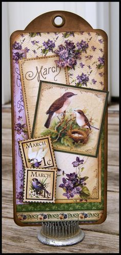 a close up of a card on a table with flowers and birds in the background