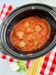 meatballs in marinara sauce in an instant pot with noodles on the side and a red checkered tablecloth