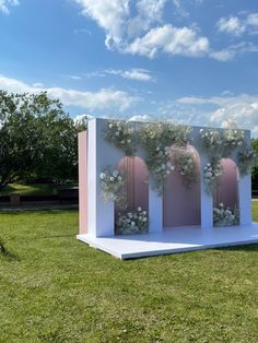 a white structure with flowers on it in the grass