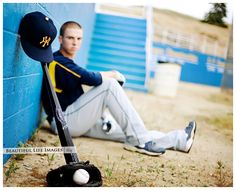 a baseball player sitting next to a blue wall with a bat and ball on it