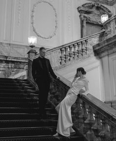 a man and woman standing at the top of some stairs