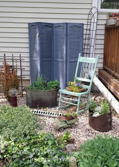 a rocking chair sitting on top of a gravel covered ground next to a planter filled with flowers