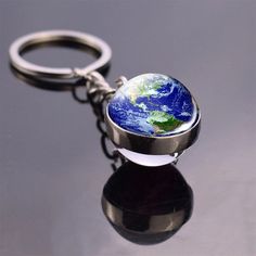 a keychain with the earth on it sitting on top of a black surface