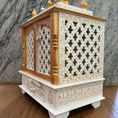 an ornate white and gold box on top of a wooden table next to a marble wall