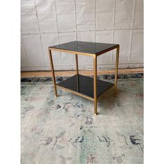 a black and gold end table on a rug