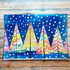 an art project made with colored paper and watercolors on wood planks, depicting christmas trees in the snow