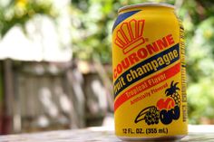 a close up of a can of beer on a wooden table with trees in the background