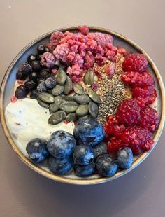 a bowl filled with berries, yogurt and granola on top of a table