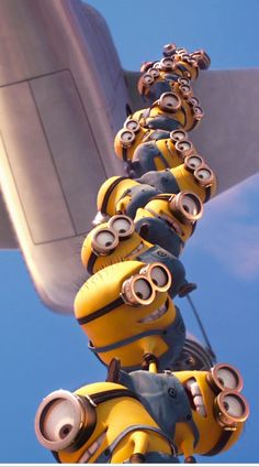 a group of minion characters hanging from the side of an airplane