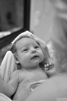 a black and white photo of a baby in a bathrobe looking at the camera