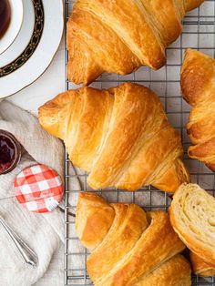 several croissants on a cooling rack next to a cup and saucer