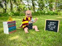 a baby sitting in the grass next to a sign that says i solemnly swear that i am up to no good