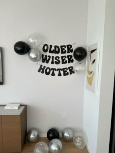 some balloons are hanging on the wall in a room with white walls and black and silver decorations