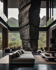 a living room with large rocks on the wall and floor to ceiling windows overlooking mountains