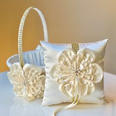 two white flower pillows sitting on top of a table next to a basket filled with flowers