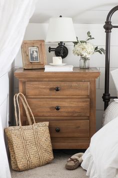 a bedroom with a bed, dresser and lamp on it's side table in front of a window