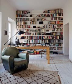 a living room filled with lots of books on top of a book shelf next to a desk